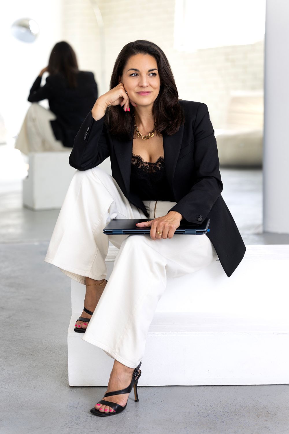 Marta Pálešová sedí na bielom podstavci s notebookom